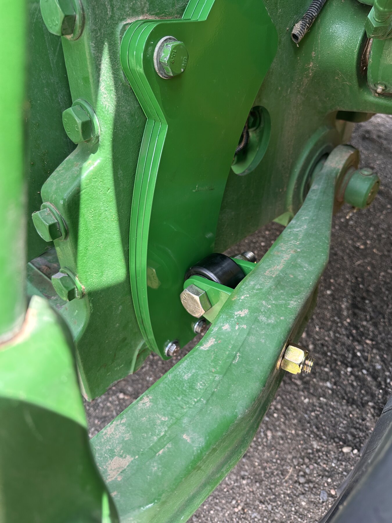 RollerGlide Precision close-up &mdash; industrial cam follower bearing and precision-machined bracket on John Deere 8R